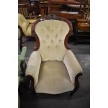 A Victorian mahogany easychair, having a deep button spoon back surmounted with carved cresting over