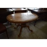 A Victorian carved and inlaid pedestal loo table, quarter veneered with central inlaid oval
