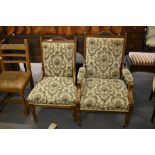A pair of Victorian oak his and hers easy chairs, with arched and scrolled carved crest rail between