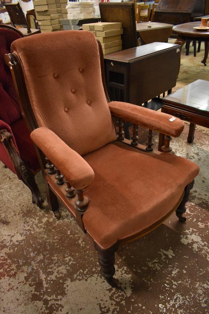 A Victorian upholstered mahogany easy chair, with turned rails, padded arms and bow fronted seat,