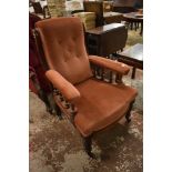 A Victorian upholstered mahogany easy chair, with turned rails, padded arms and bow fronted seat,