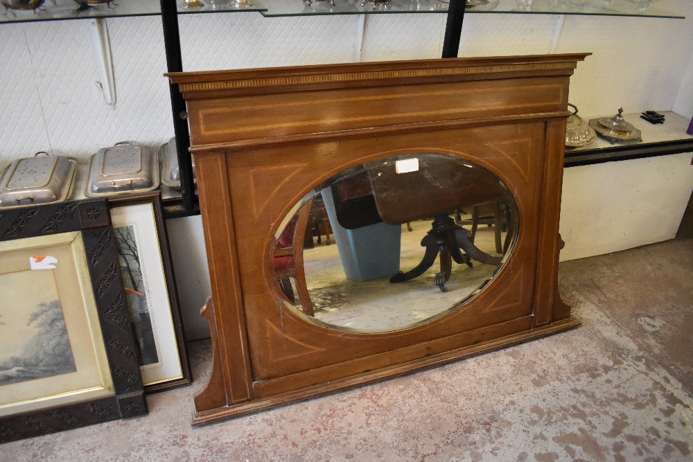 And Edwardian inlaid mahogany overmantel mirror, having dentil inlaid surmount and bevelled oval