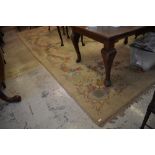 A large floral patterned machined room carpet, patches of moth damage throughout some losses to