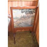 An Edwardian mahogany firescreen, inset with painted silk Oriental rural scene raised on slender