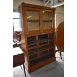 A Victorian light oak bookcase, having a moulded surmount over two glazed cupboard doors, the