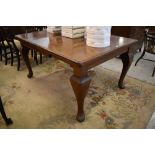 An early 20th century mahogany extending dining table with moulded edge detail and bulbous cabrial