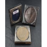 A group of three small silver mounted photograph frames, each of rectangular form with oval aperture