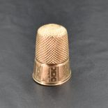 An early 20th century yellow metal thimble, stamped with oak leaf mark to the exterior, indistinctly