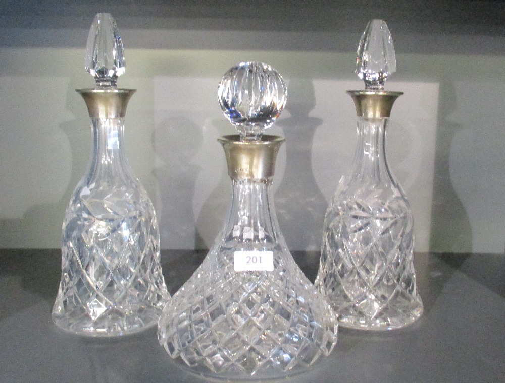 A pair of silver mounted cut-crystal decanters, having facetted stoppers over the flared silver