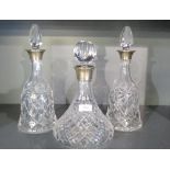 A pair of silver mounted cut-crystal decanters, having facetted stoppers over the flared silver