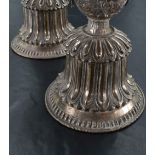 A pair of Tibetan white metal butter lamps, having flared cylindrical bowls with moulded