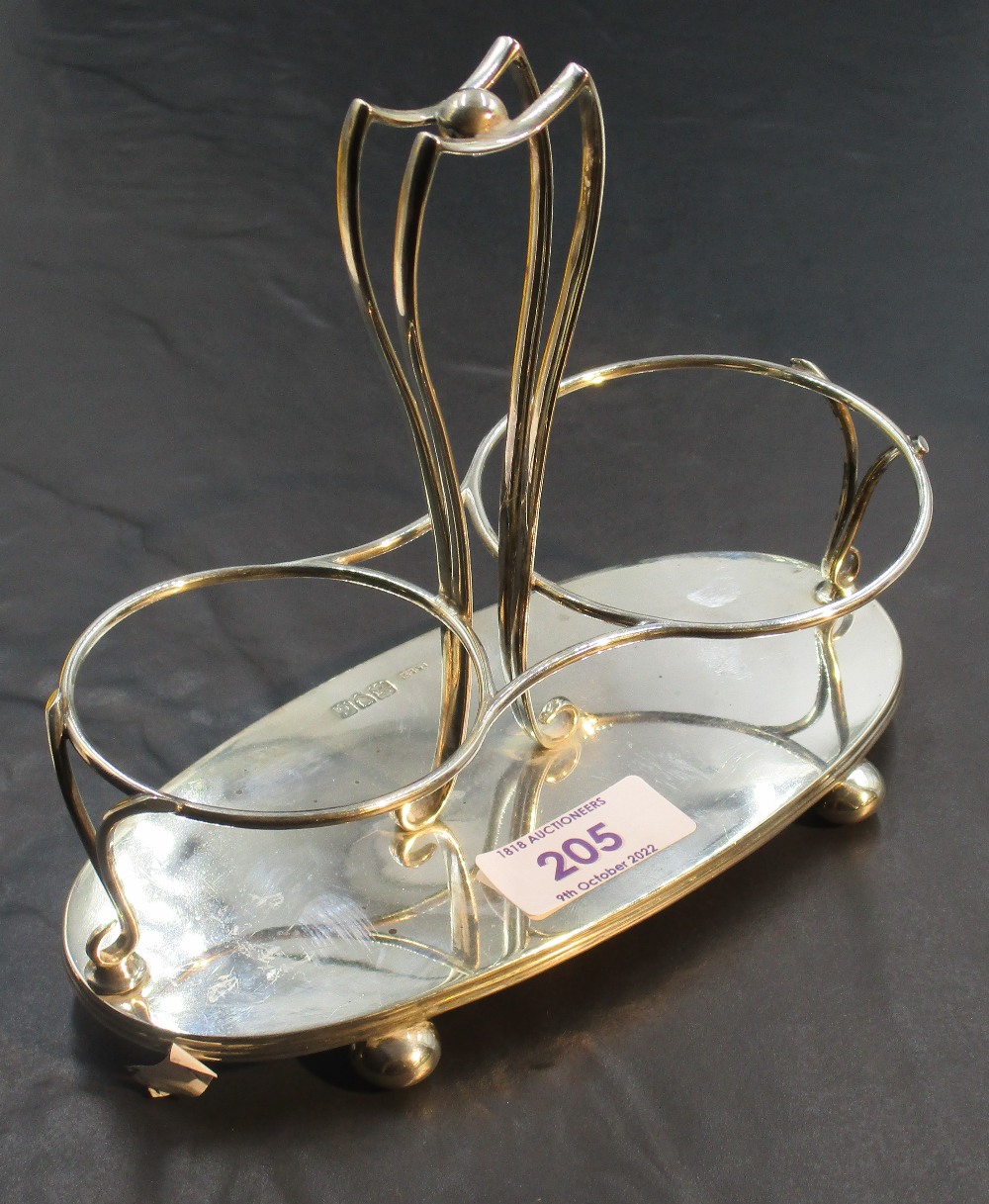 A late Victorian silver bottle stand, having a central shaped and pierced handle between two