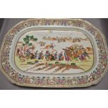 A large Chinese porcelain charger decorated with scenes of Oriental merchants at dock side in a