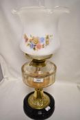 A late 19th/ early 20th century oil lamp having glass reservoir and floral shade.