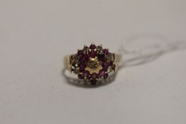 A ruby and diamond chip triple cluster ring in a claw set basket mount with engraved shoulders on
