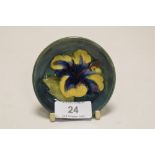 A modern Moorcroft pin dish of small size in a green glaze with peony decoration measuring 8cm