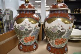 A pair of 20th century Japanese porcelain lidded temple urns or jars decorated with peacocks