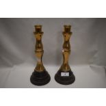 A pair of solid brass candlesticks on ebonised turned wood bases