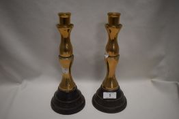 A pair of solid brass candlesticks on ebonised turned wood bases