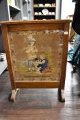 A Victorian fire screen having embroidered picture of Martha Morphet's work 1859 with oak surround