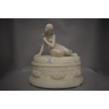 An early 20th century marble sculpture of a nude maiden reclining on a garland and floral base