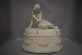 An early 20th century marble sculpture of a nude maiden reclining on a garland and floral base
