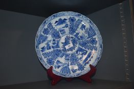 A large Chinese export charger plate decorated with panels of landscape and prunus bearing four