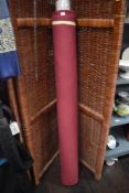 A roll of haberdashery or upholsterers fabric in burgundy