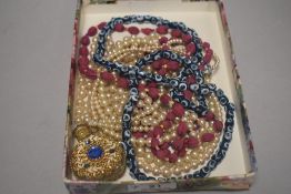 A collection of beads and a perfume bottle having filigree detail and blue gem stones.
