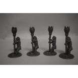 A set of four late Victorian fairytale themed candlesticks in the form of gnomes holding tulip