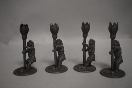 A set of four late Victorian fairytale themed candlesticks in the form of gnomes holding tulip
