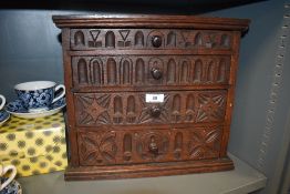 An early 20th century oak cased chest of small drawers having carved Jacobean style frontage