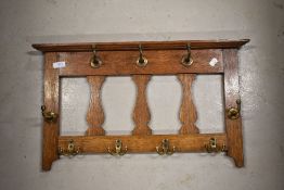 An Arts and Crafts golden oak wall mounted coat rack
