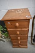A narrow pine chest of five drawers