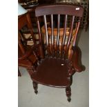 A traditional dark stained Windsor style arm chair having turned legs and H strecther