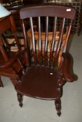 A traditional dark stained Windsor style arm chair having turned legs and H strecther