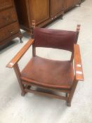 An Arts and Crafts oak and leather low armchair, labelled 'THE FIRESIDE CHAIR'