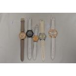 Five watches all having white straps.