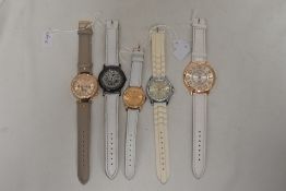 Five watches all having white straps.
