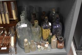 A selection of vintage advertising glass bottles in various colours and sizes