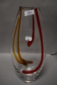 A modern studio art glass vase with red and yellow swirls on a heavy set clear body