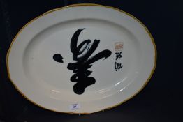 A modern ceramic serving plate of oval form with an Oriental design