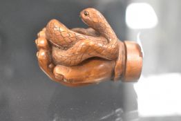 An early 20th century Japanese carved wood Netsuke of a human hand holding a Snake