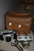 A Synchro - Compur and a Baldinette II camera with bag, and a military issue gas mask