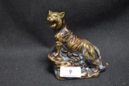 An Oriental brass tiger study depicted mid roar and climbing a ledge.