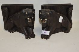 A pair of 20th century wooden carved book ends in the form of lions. Damage to foot and part of