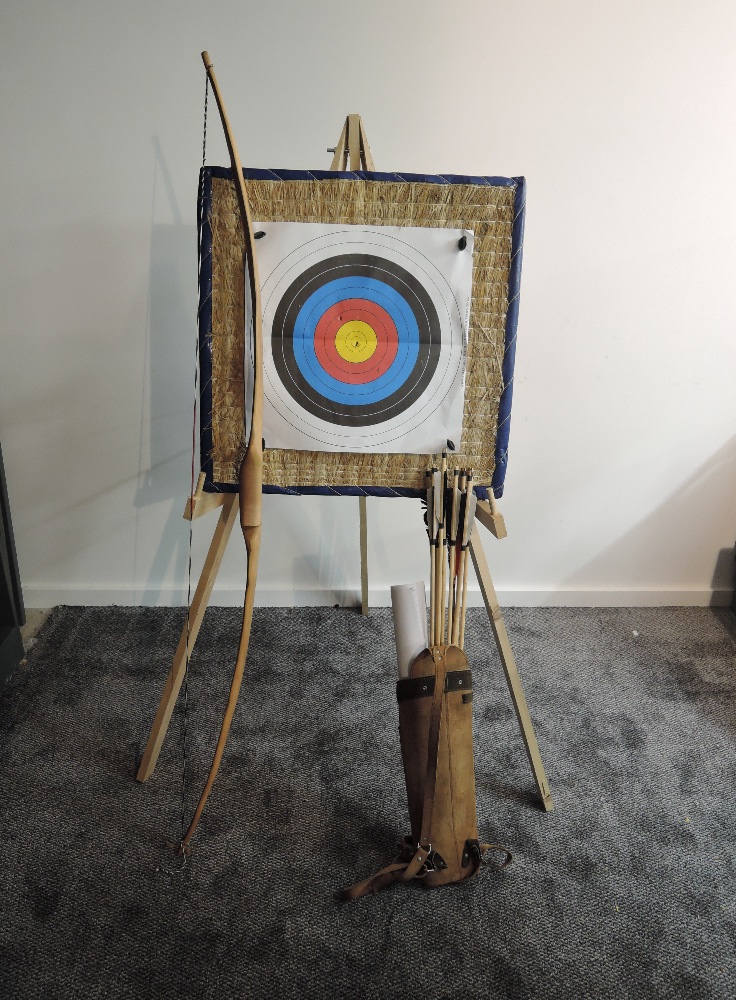 A modern Yew Wood Long Bow with arrows, target and stand