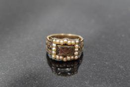 A yellow metal mourning ring having a plaited hair panel within a seed pearl border and