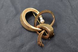 A 9ct gold brooch of stylised bow form having a central seed pearl, approx 4.9g