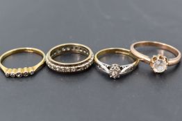 A group of four gold diamond and white stone set rings, the five stone and smaller solitaire being